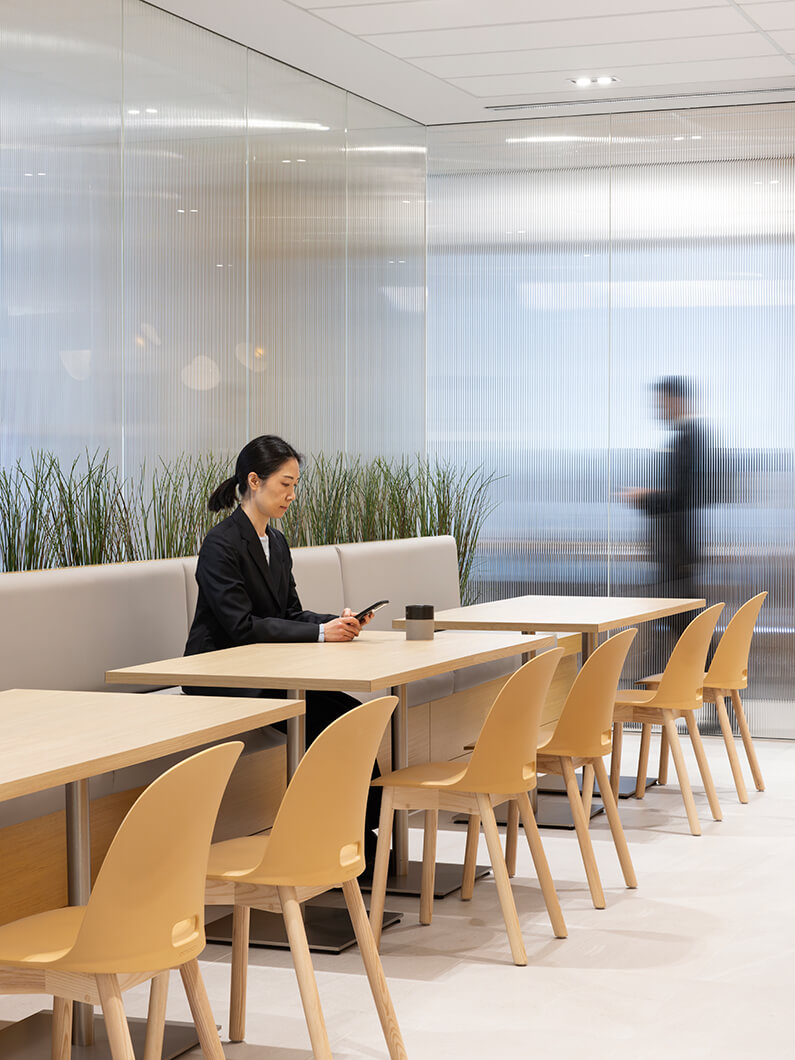 Businesswoman using smartphone in modern office cafe with minimalistic design.