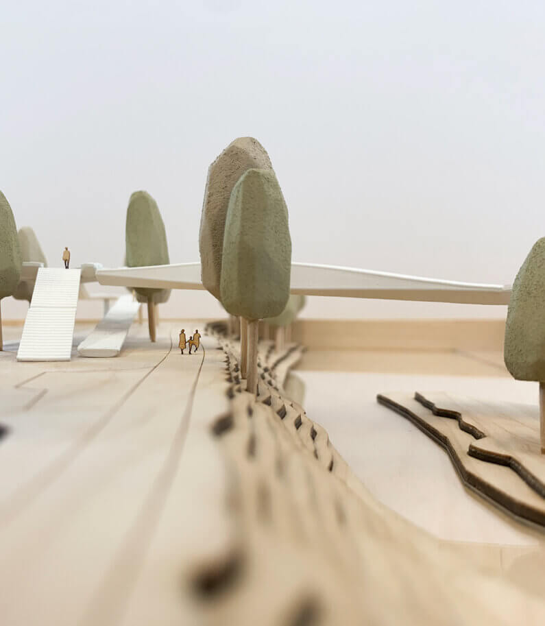 Architectural model of a landscape with bridge and pathway, featuring miniature trees.