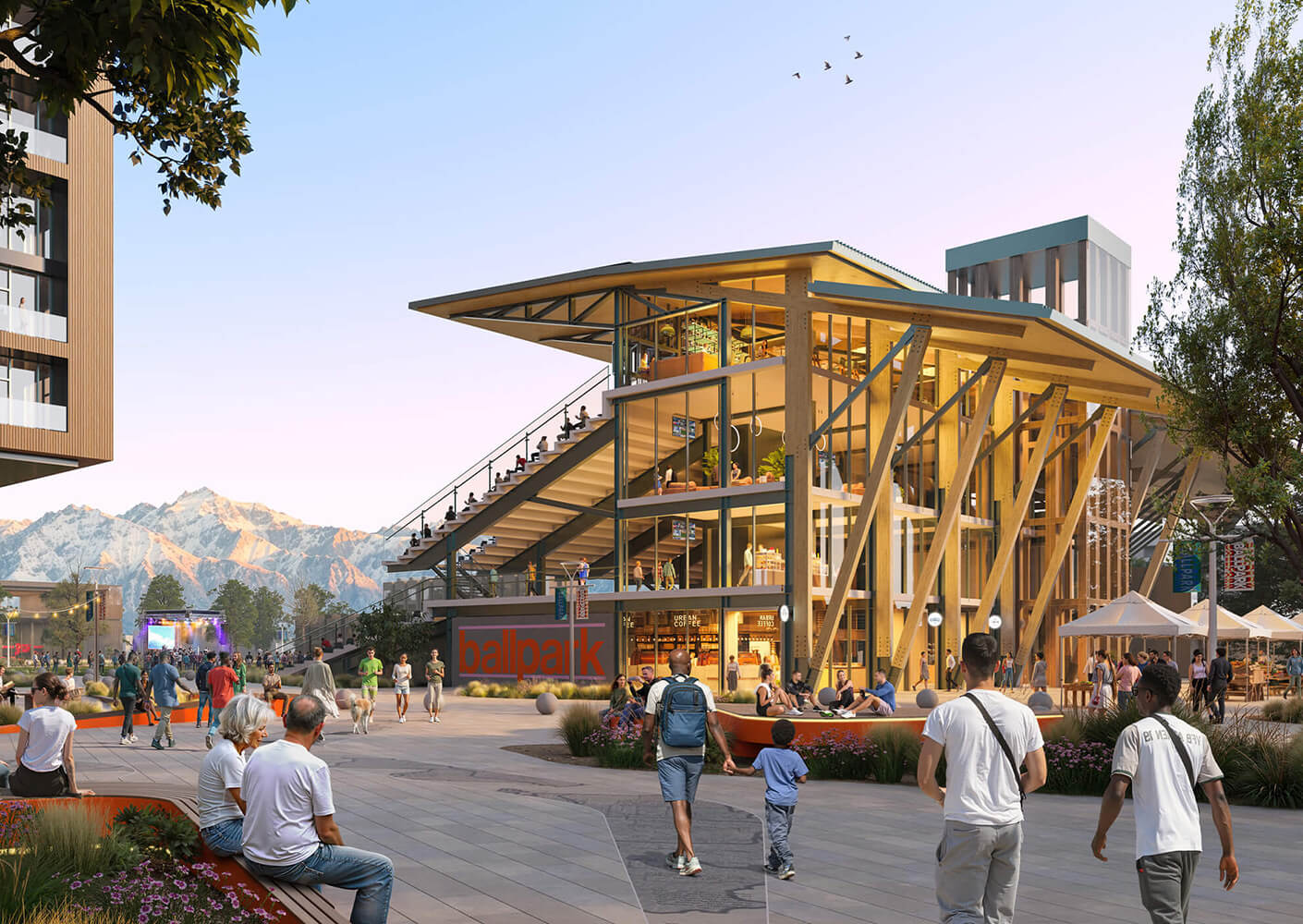 Modern outdoor plaza with glass building, mountains in background.