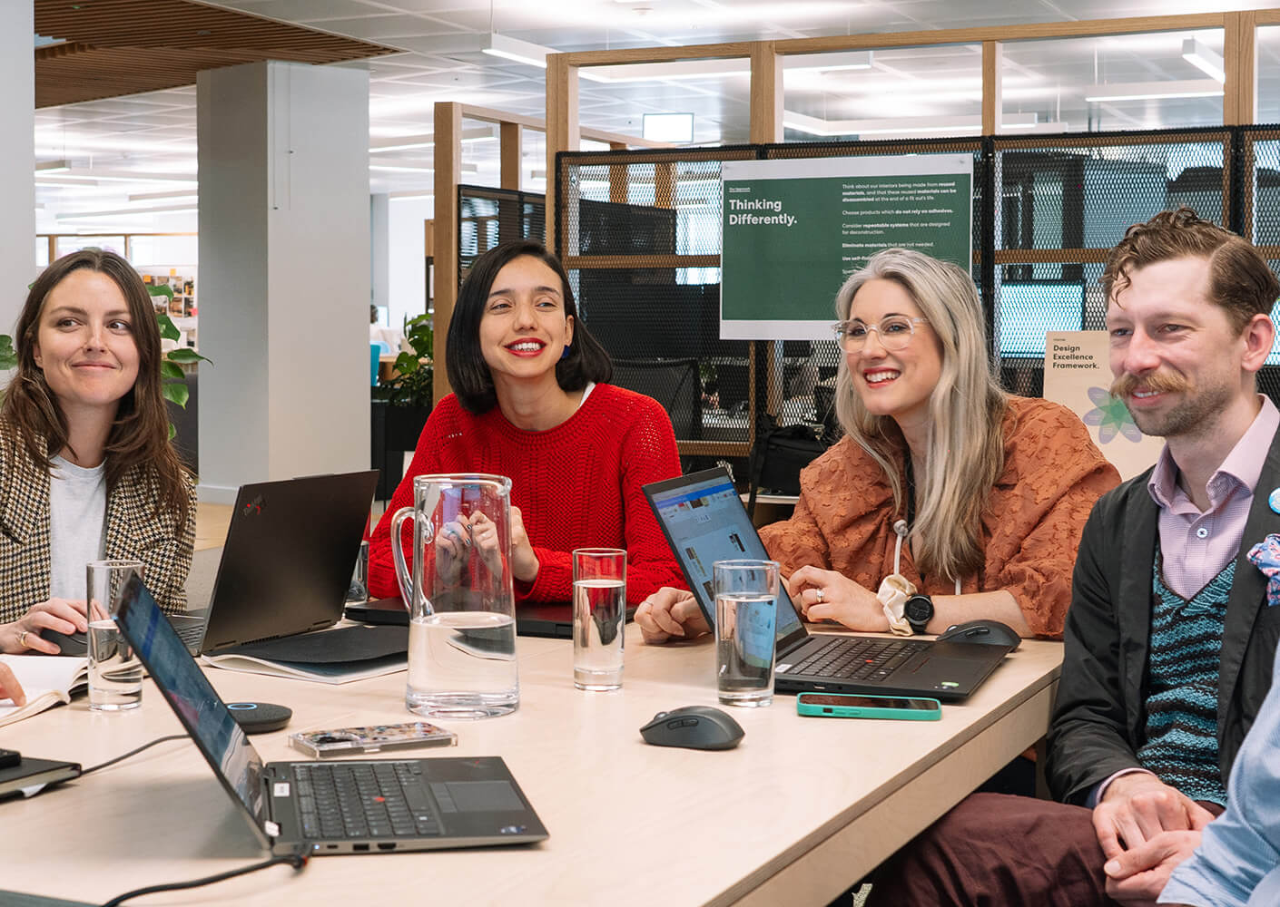 Team meeting at modern office with laptops and discussions.
