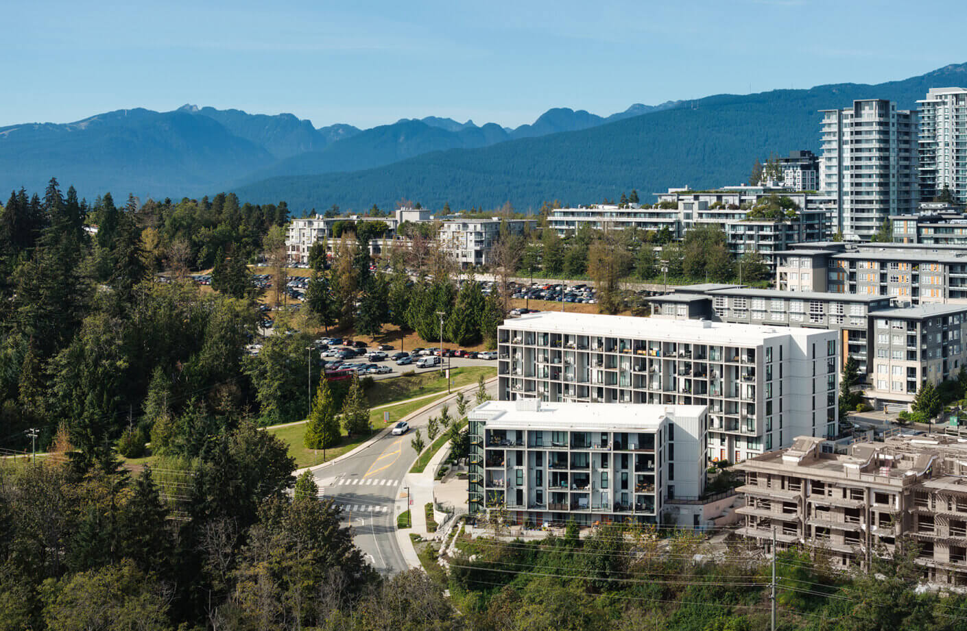 Aerial view of urban buildings with mountains and trees in the background.