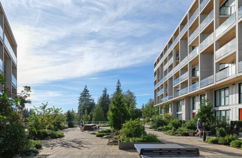 Modern apartment building with landscaped courtyard and sunny sky.
