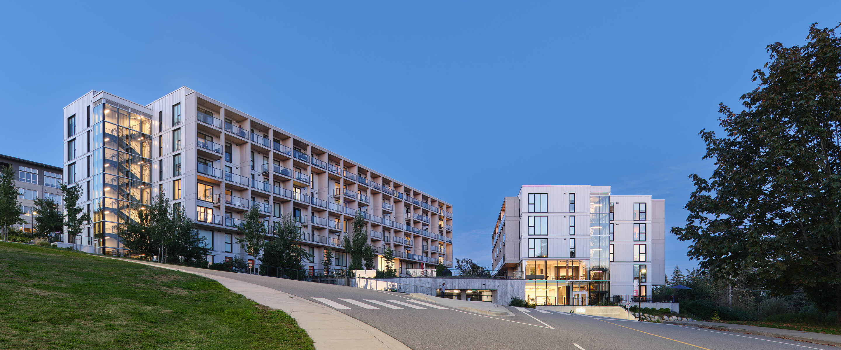 Modern apartment buildings at dusk with clear blue sky.