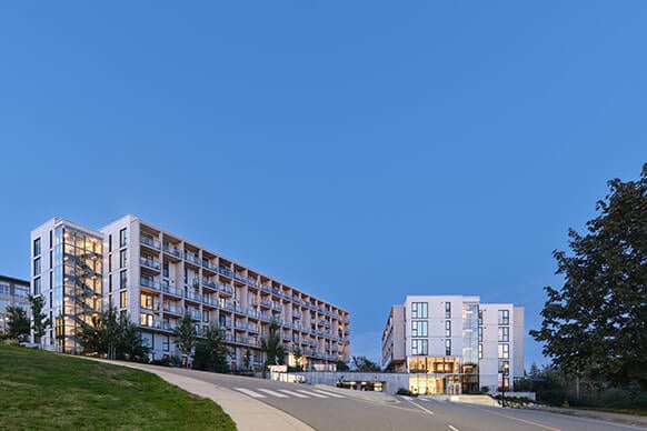 Modern apartment complex with greenery under a clear blue sky.