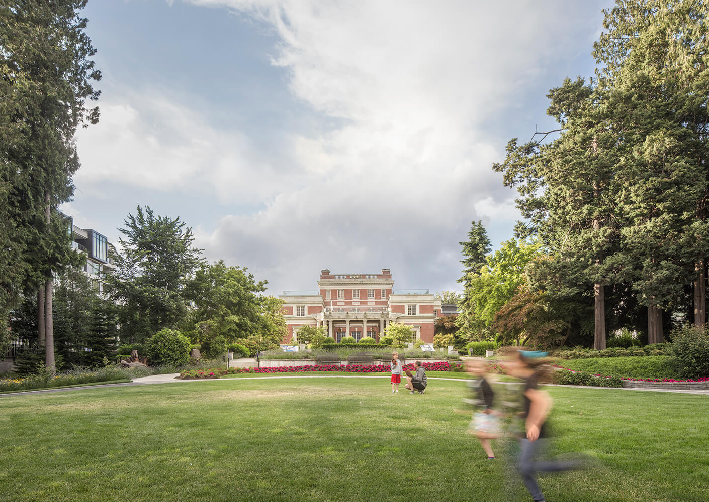 Historic mansion with lush garden and people enjoying the lawn.
