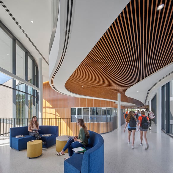 Modern school interior with students walking and studying in a bright, open space.