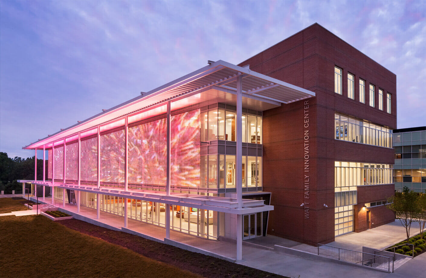 Modern innovation center building at dusk with vibrant lighting display.