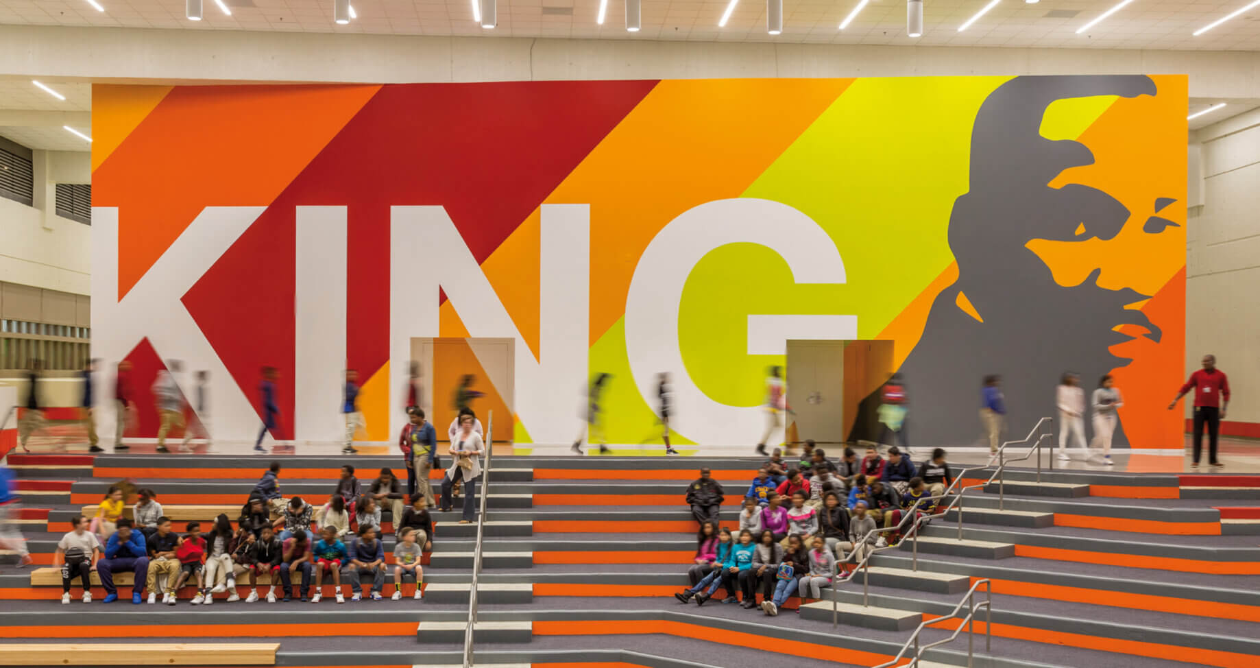 Colorful KING mural with students on steps in a school interior.