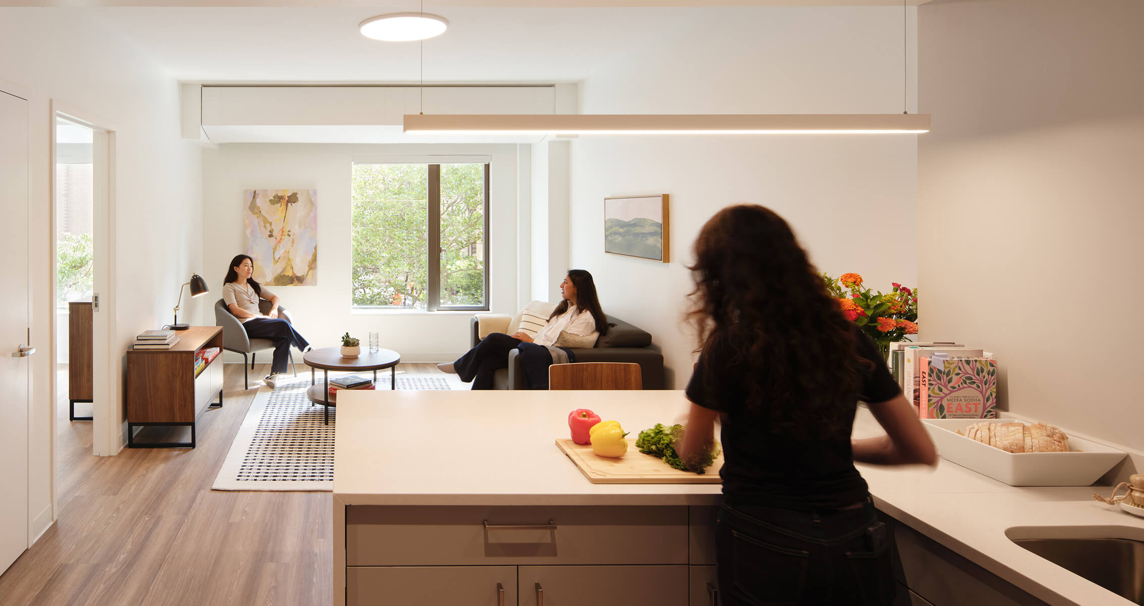 Student residence kitchen and living area with residents relaxing and preparing food.