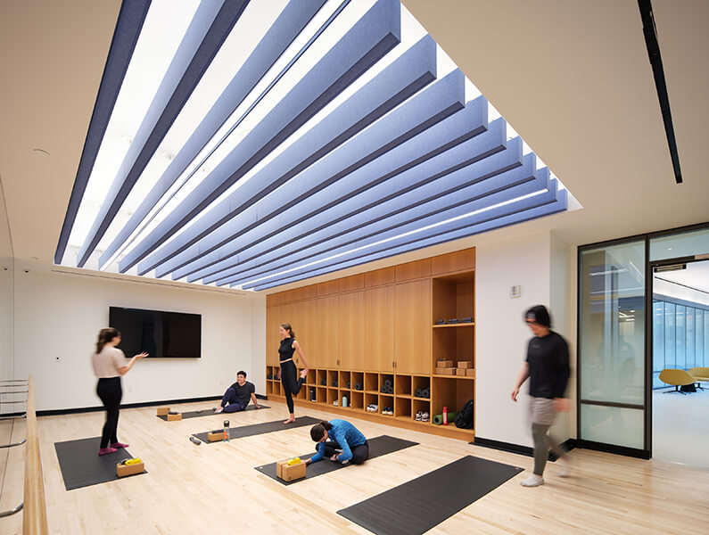 Yoga studio with people practicing on mats, wooden storage and sleek lighting.