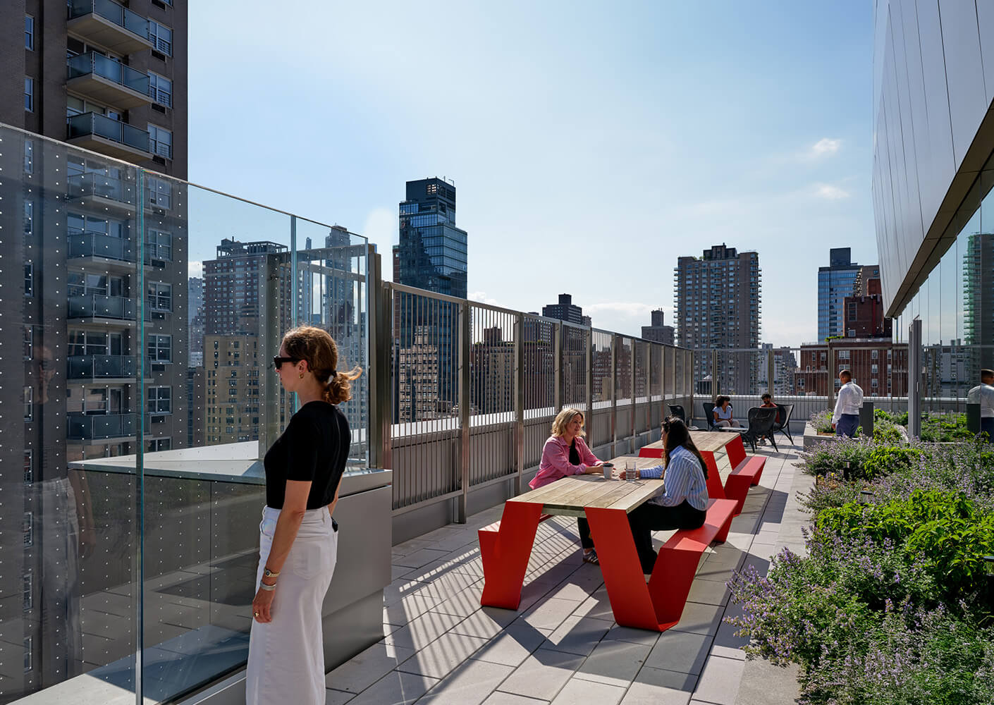 Rooftop terrace with people enjoying views and modern seating, surrounded by cityscape.
