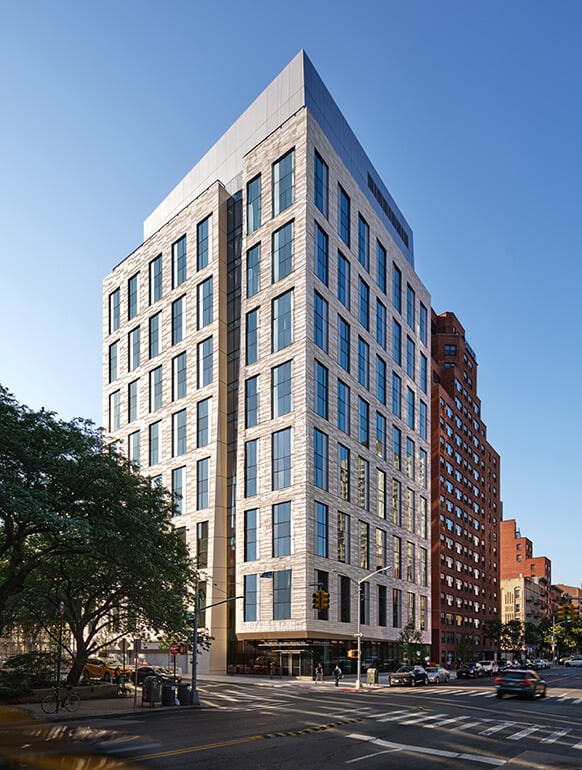 Modern medical student residence hall on a sunny day at an intersection in New York City.