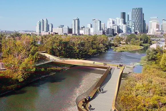 View of a modern bridge over a river with a city skyline in the background.
