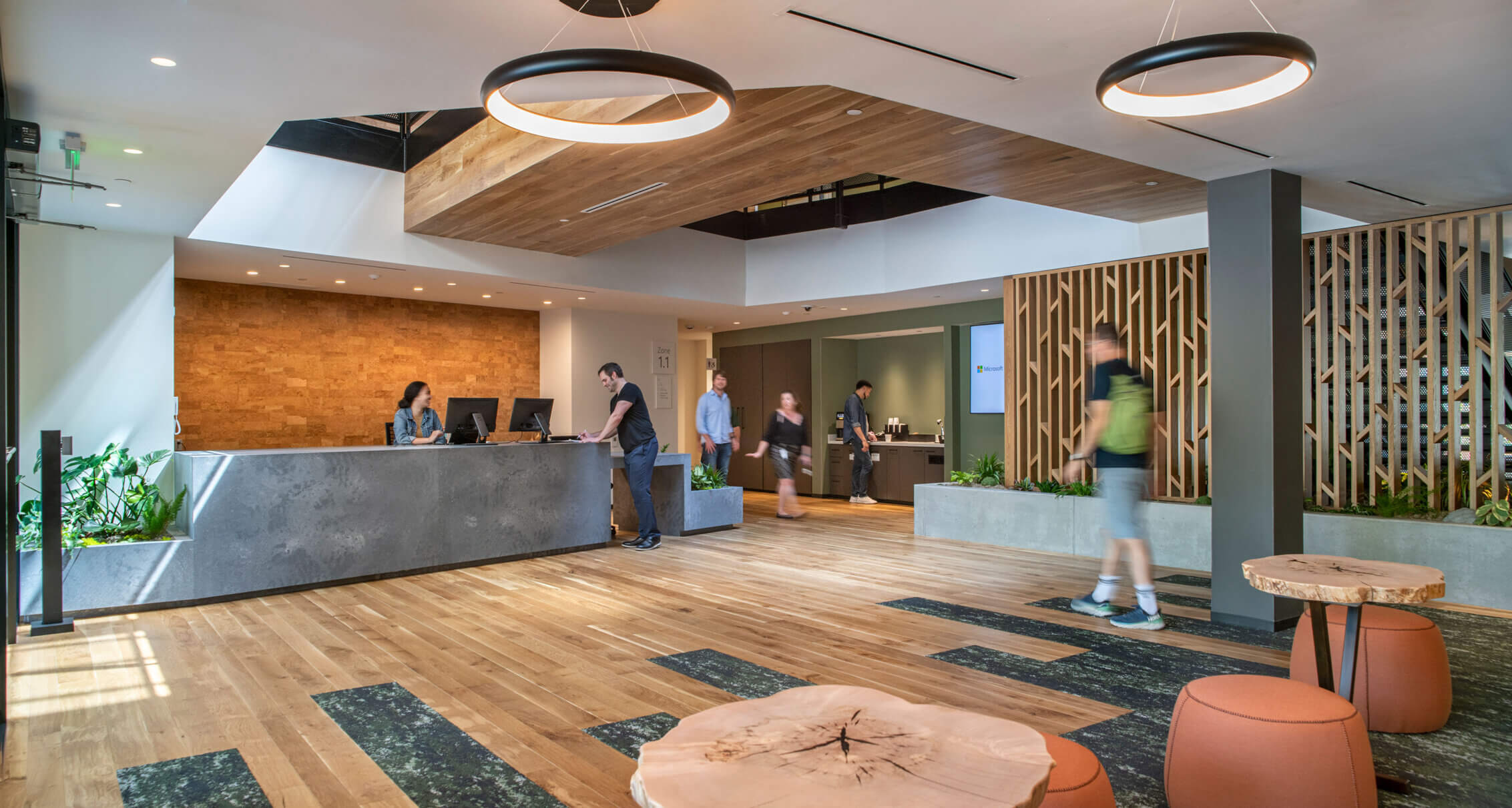 Modern office reception area with wooden decor and people at a desk.