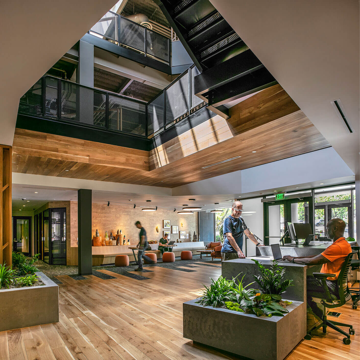 Modern office lobby with natural light, plants, and people working.