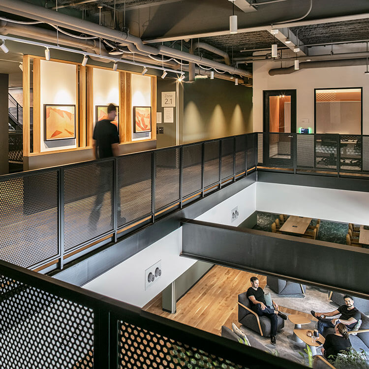 Modern office interior with artwork and lounge area on a mezzanine level.