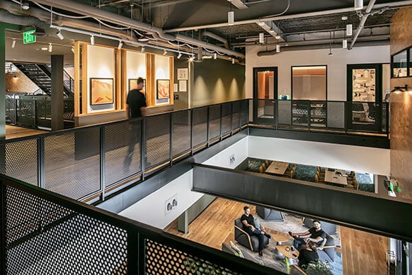 Modern office interior with open spaces, artwork, and people interacting.