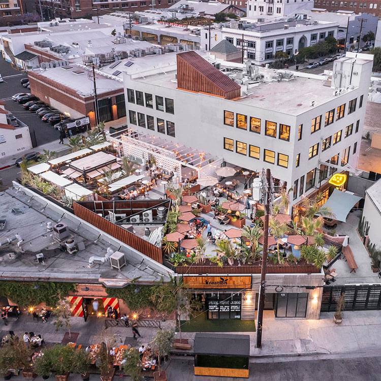Aerial view of vibrant urban rooftop restaurant, bustling with visitors and outdoor seating.