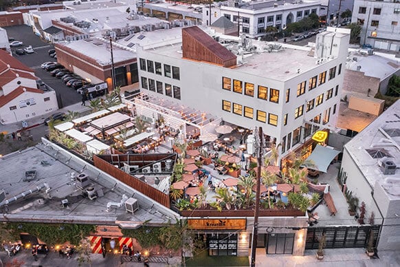 Aerial view of urban rooftop restaurant with outdoor seating and lush greenery.