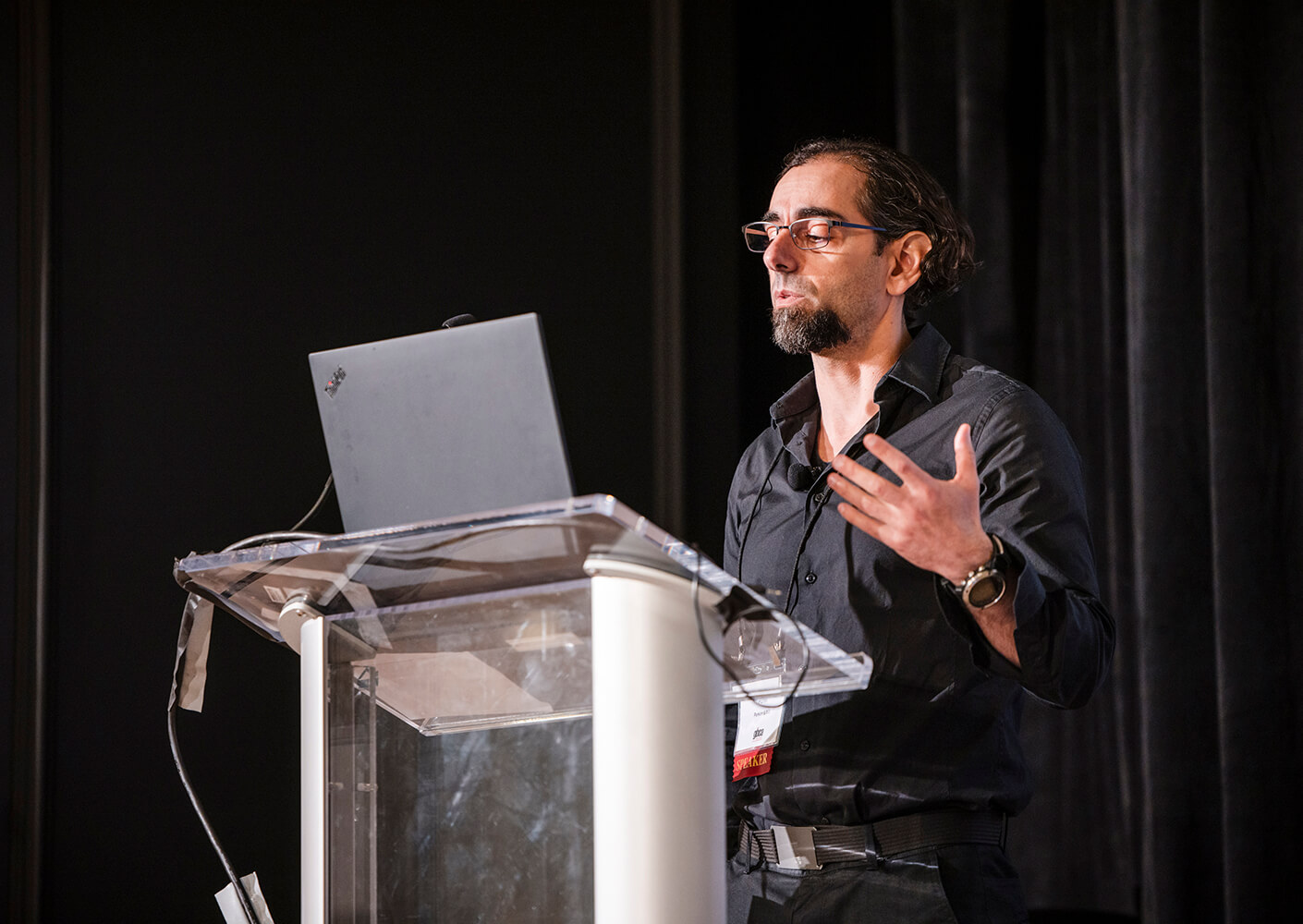 Speaker presenting at a conference, gesturing passionately from the podium.
