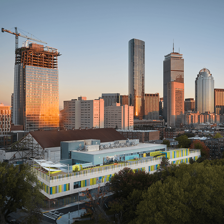 Skyline view of the City of Boston's vibrant urban landscape at sunset with the William E. Carter School in the foreground.