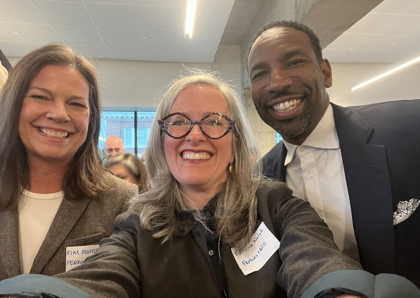 Group selfie at a professional event featuring smiling attendees in a bright venue.