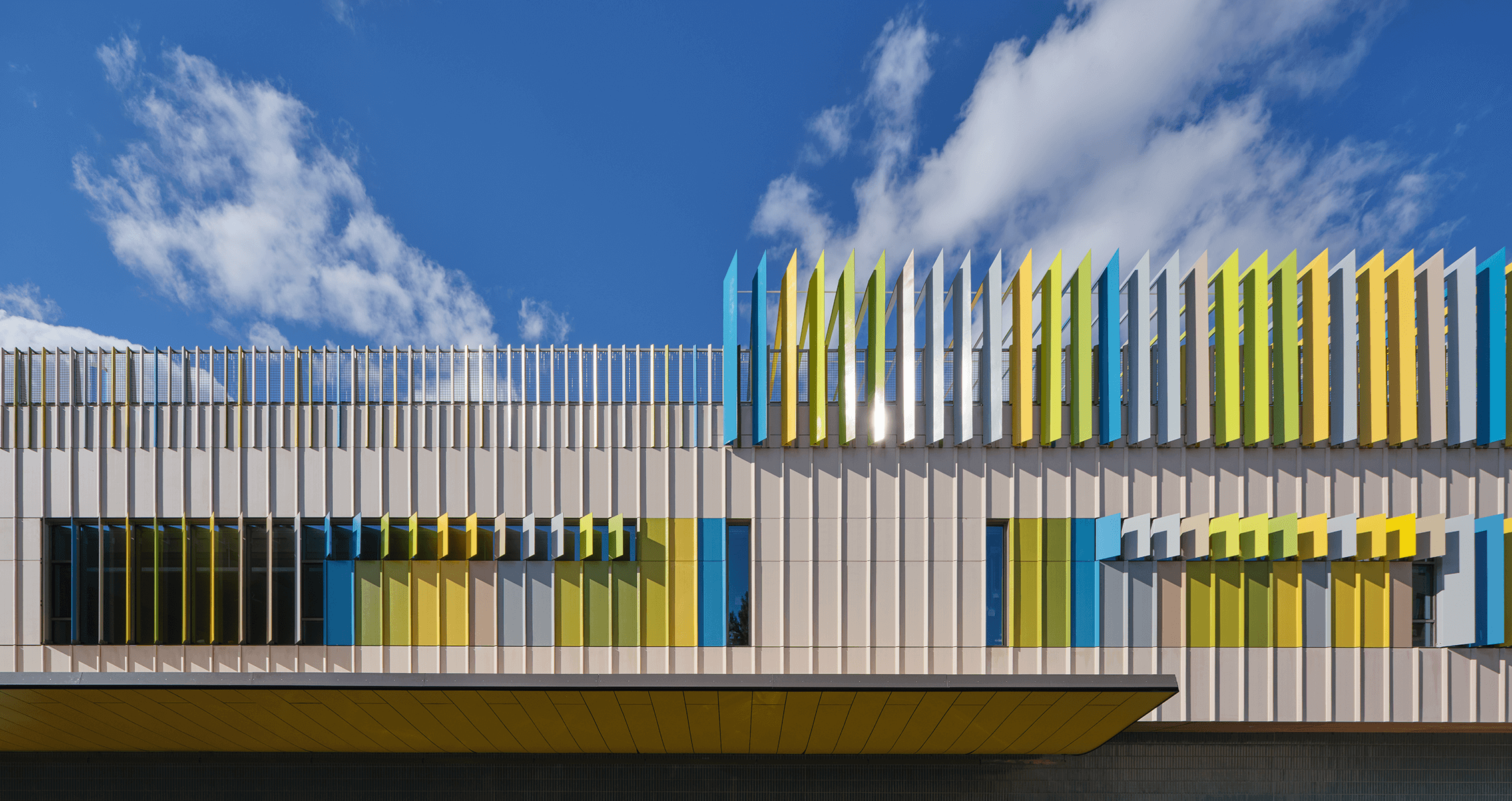 Colorful modern architectural facade of the William E. Carter School under a blue sky with clouds.