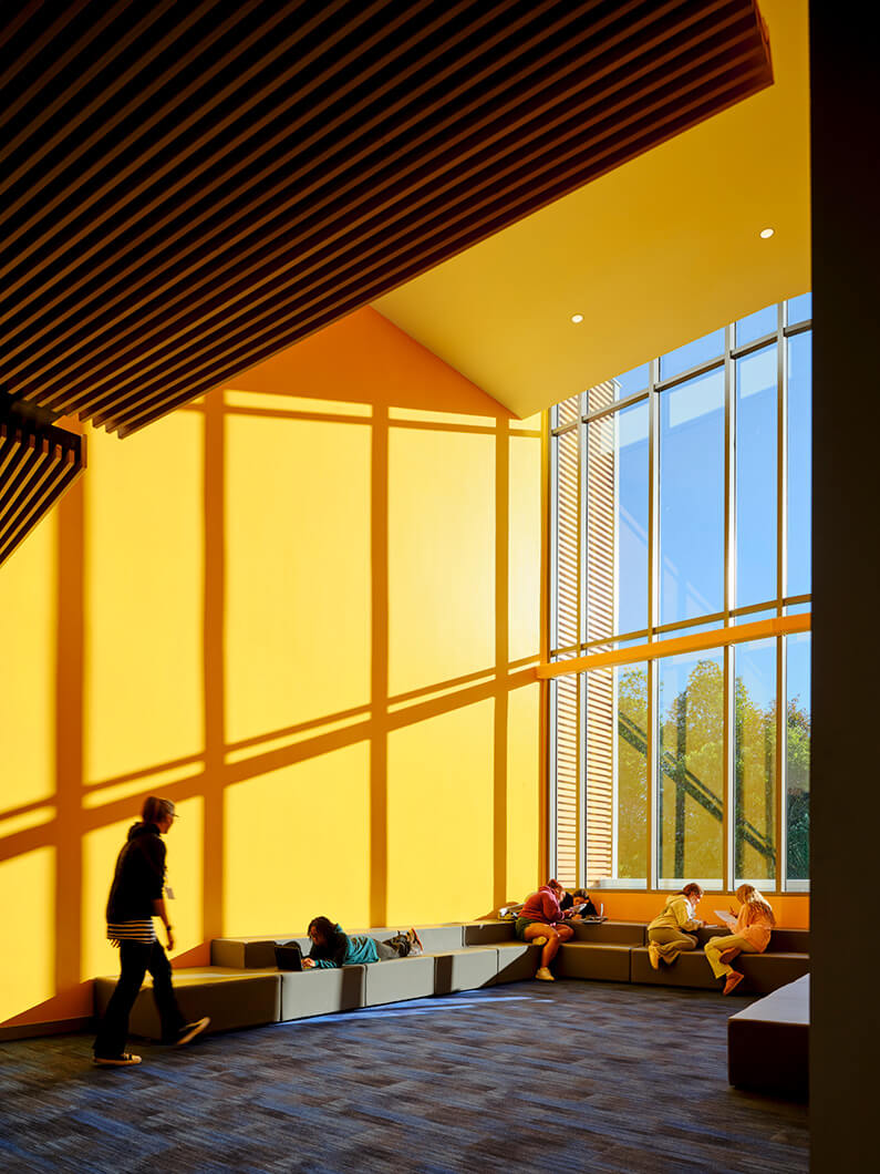 Bright, modern study space with students engaged in reading and using laptops.