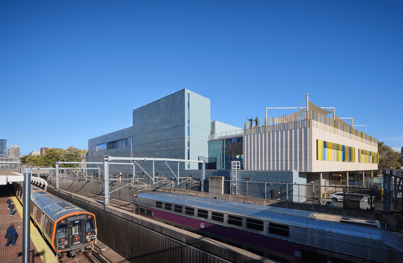 Modern train station with unique architecture and the William E. Carter School under a clear blue sky.