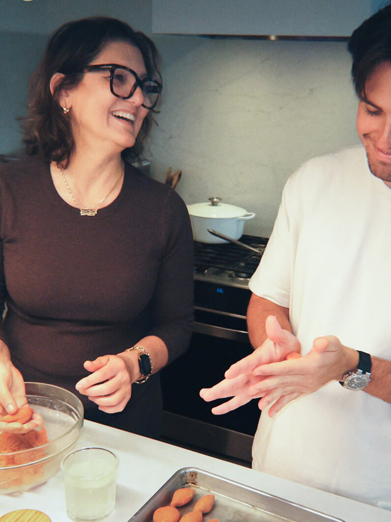 Two people laughing together while cooking in a cozy kitchen.