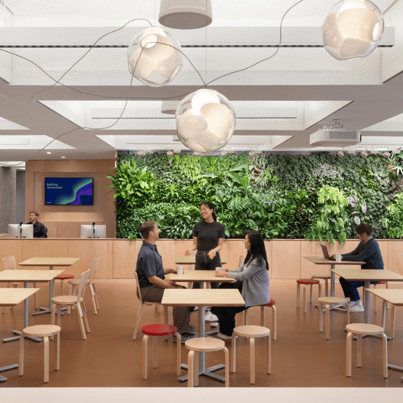 Modern cafe interior with greenery, tables, and people engaging in conversation.