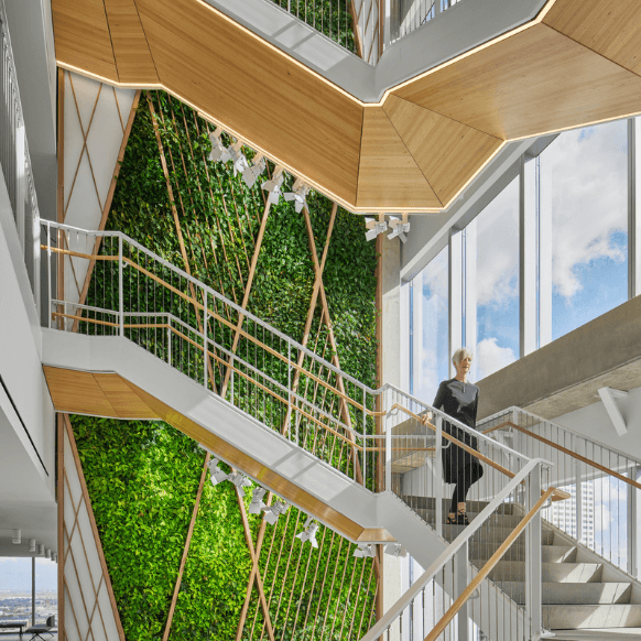 Modern staircase with greenery and a woman in business attire, showcasing eco-friendly design.