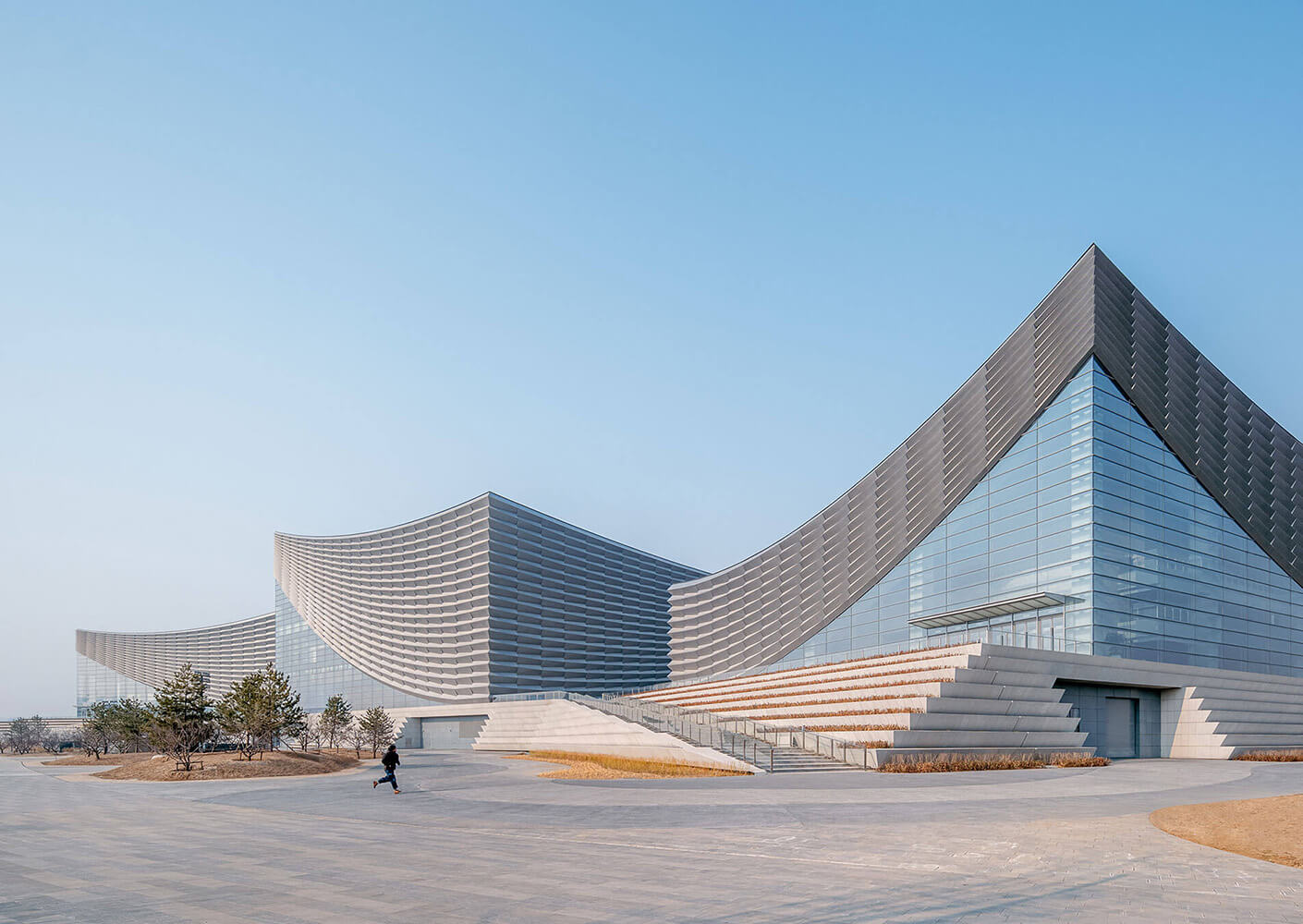 Modern opera house with sleek, curved design against a clear blue sky.