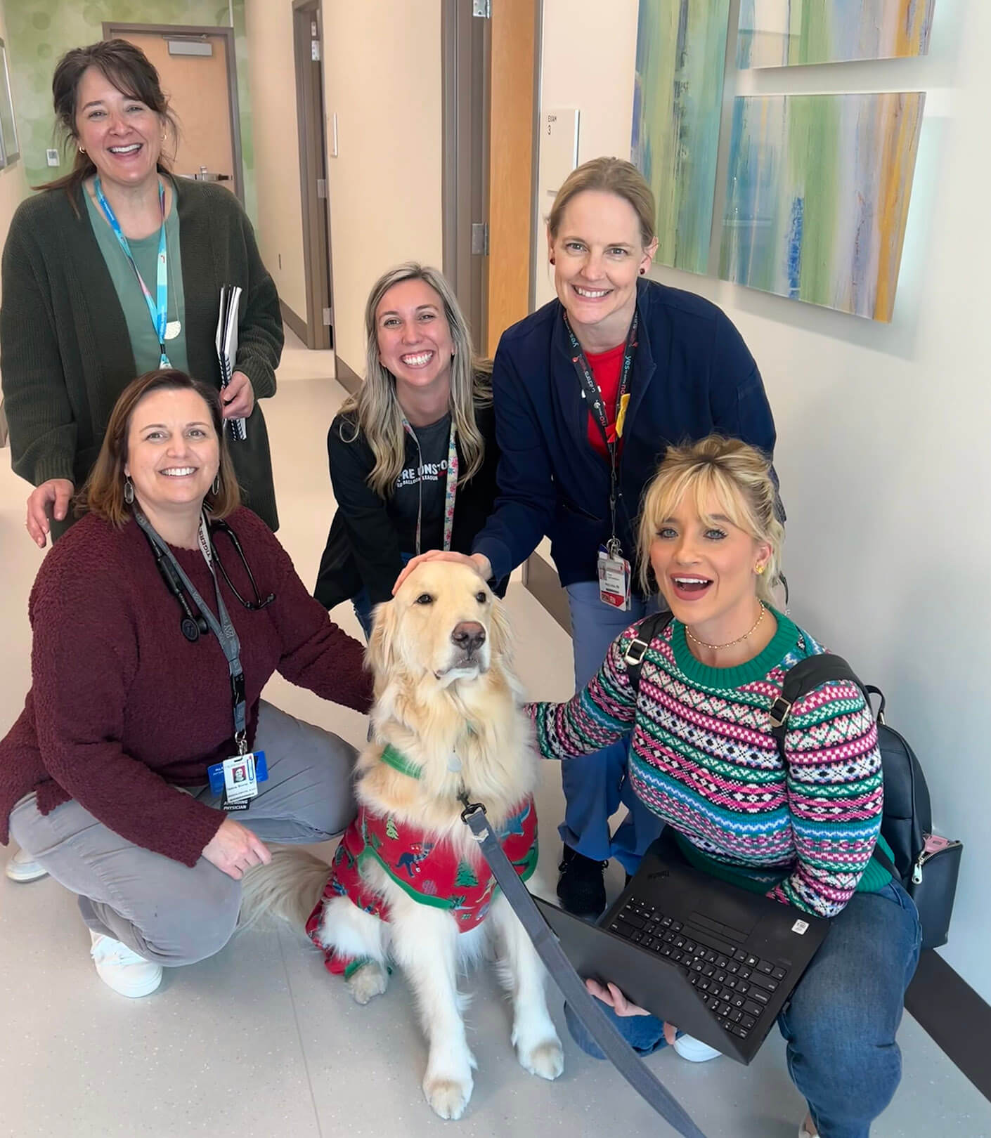 Therapy dog with caregivers and Andrea, spreading joy in a healthcare setting during the holidays.