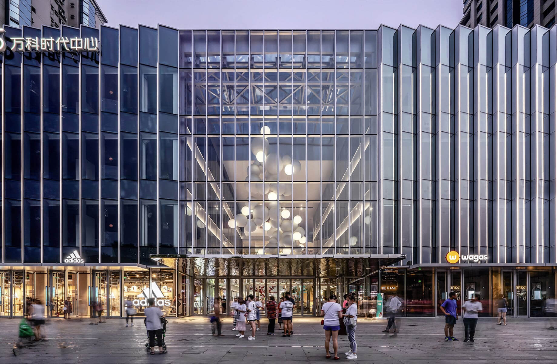 Urban architecture featuring a sleek glass façade, intricate lighting, and geometric lines, blending transparency with vibrant street activity.