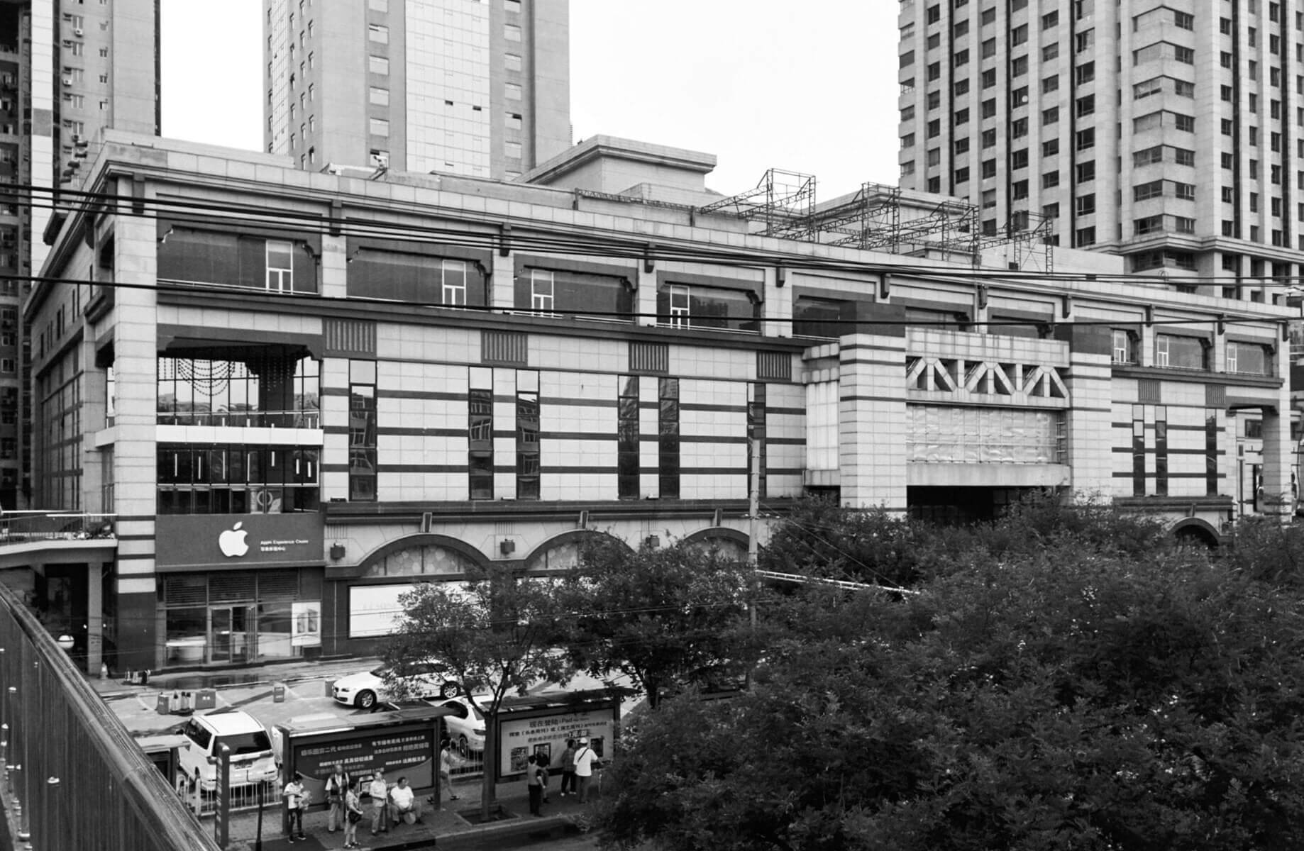 Urban structure showcasing layered stone textures, large windows, and distinctive geometric detailing, set against a skyline of towering buildings.