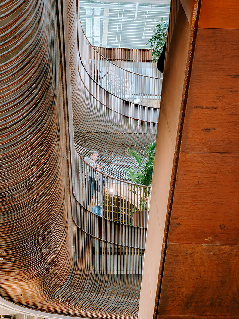 Elegant architectural staircase with curved railings and greenery. Modern interior design.