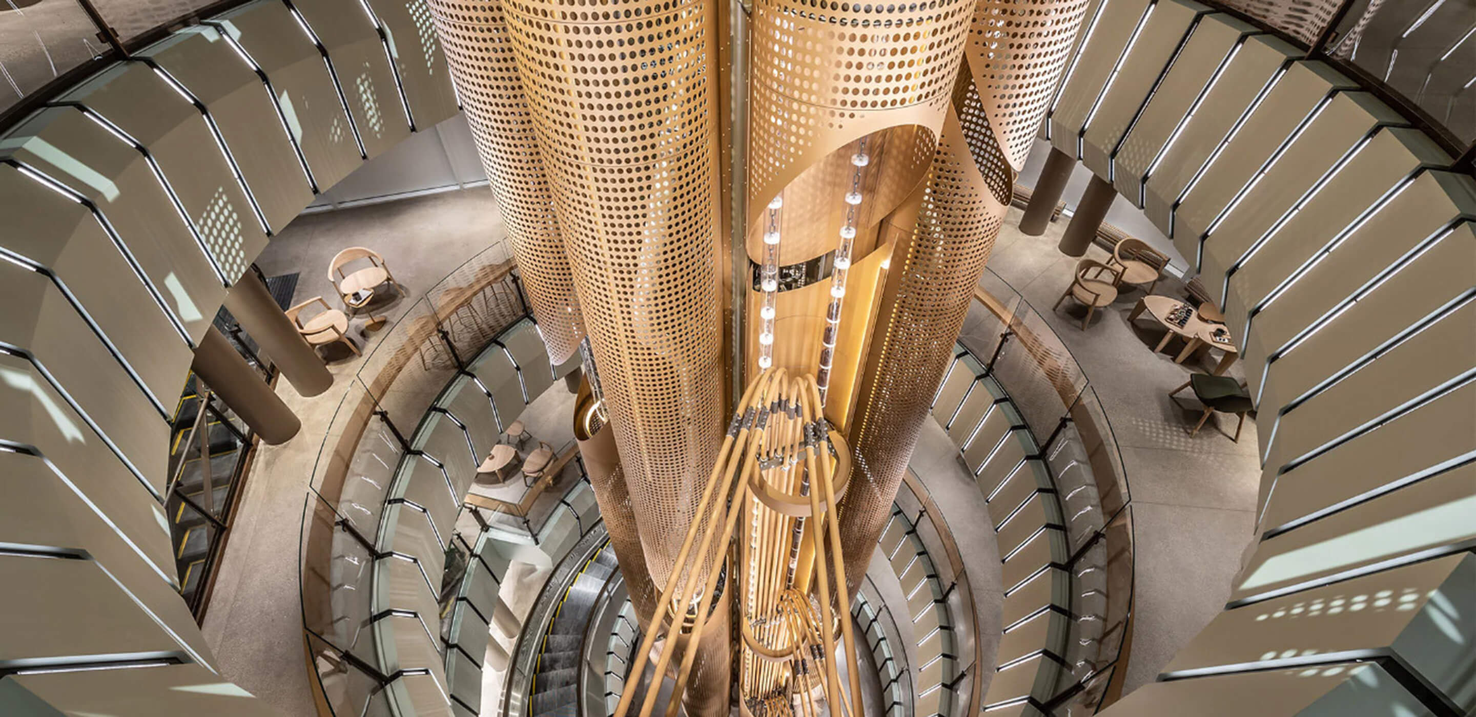 Modern architectural atrium with circular design and wooden accents. Elegant lighting. A 56-foot-tall cask in the center contains coffee beans.