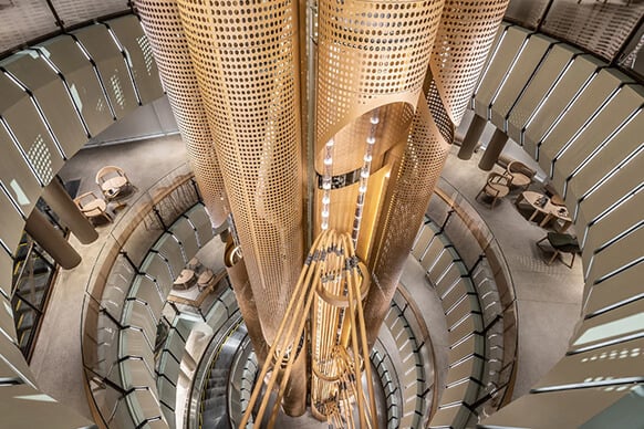 Modern architectural atrium with circular design and wooden accents. Elegant lighting. A 56-foot-tall cask in the center contains coffee beans.