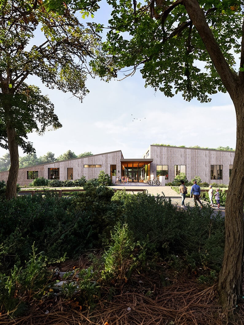 Exterior view of a building surrounded by greenery, showcasing entrance and pathways, with people walking and bicycles parked nearby.