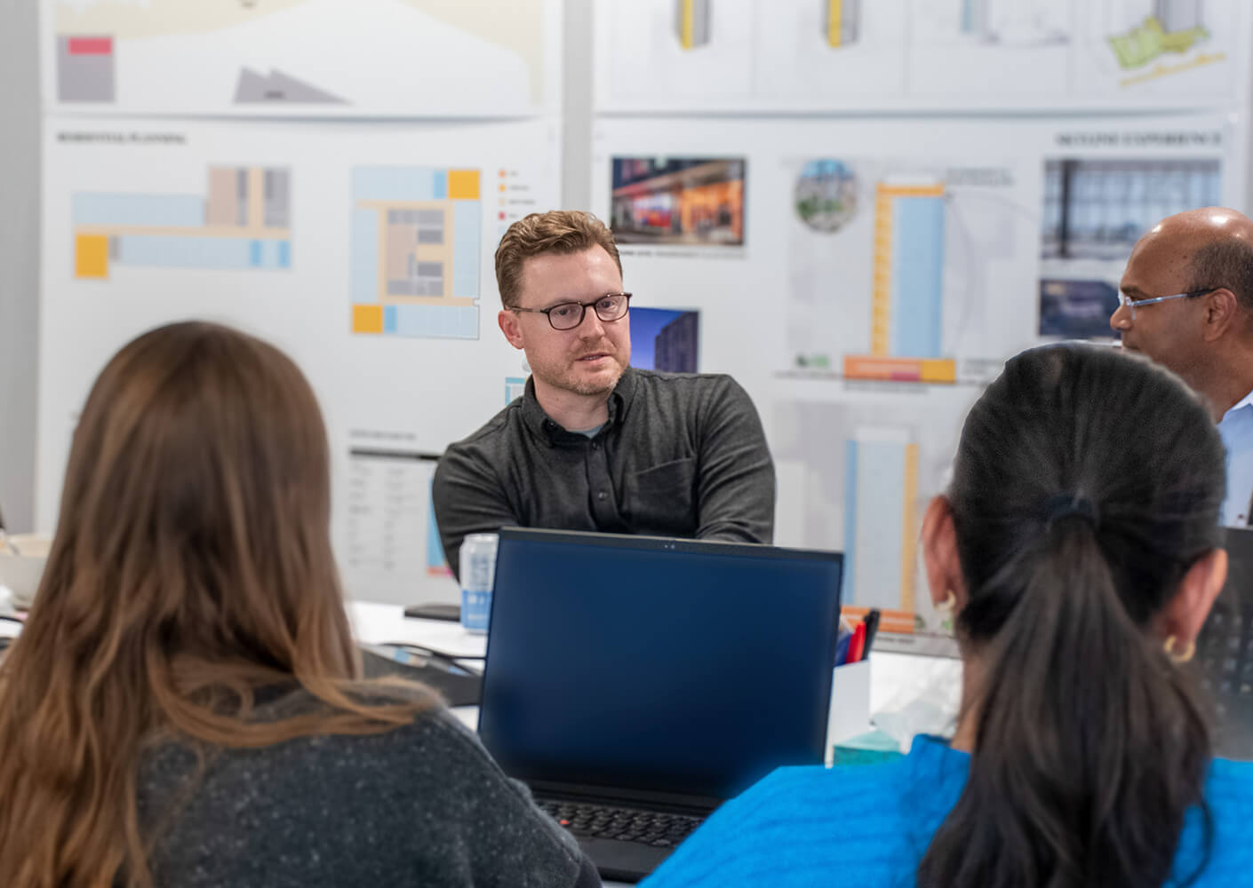Chris Karlson engaged in a discussion during a planning meeting, with architectural diagrams and a laptop in view.