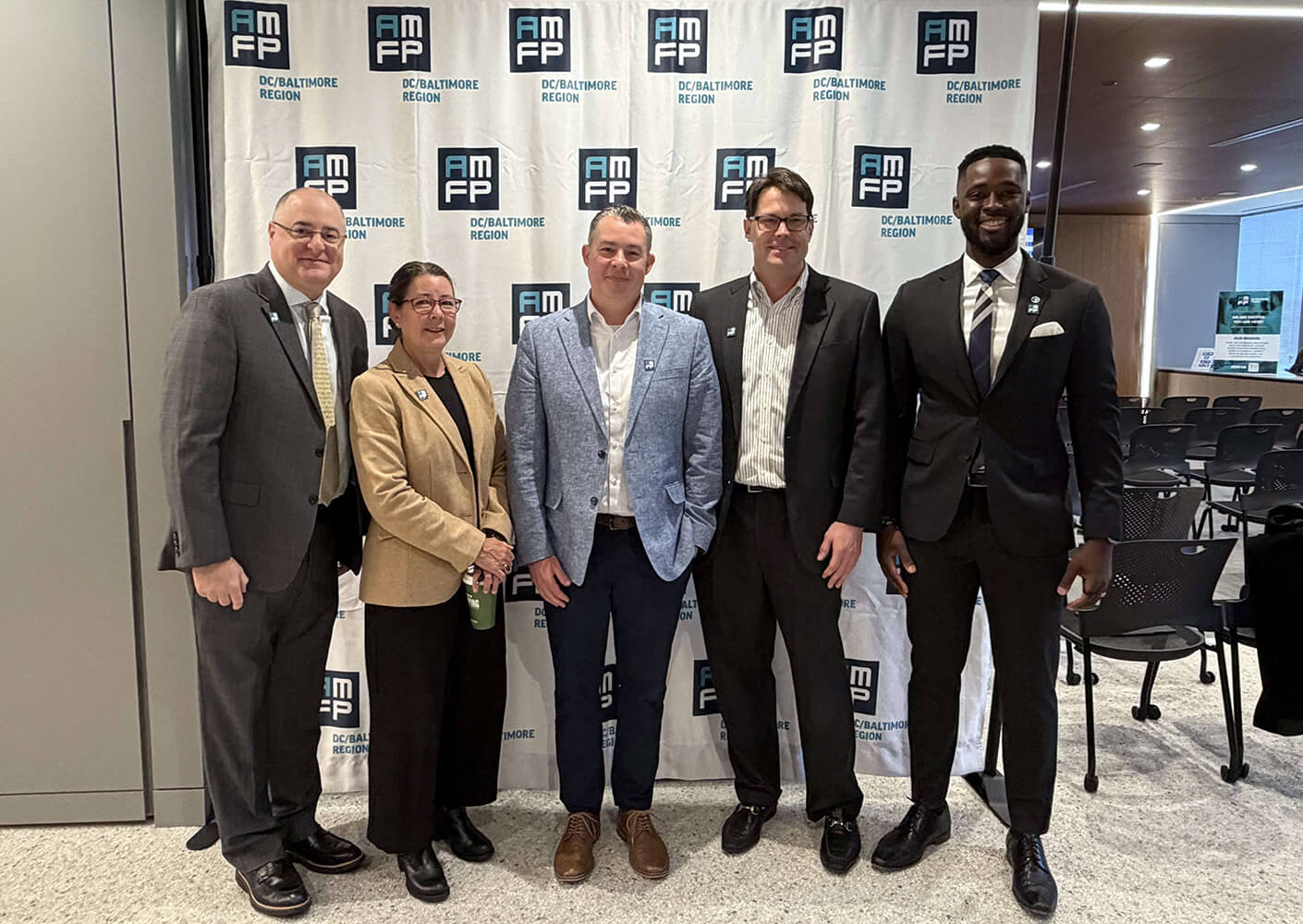 Group of five professionals posing for a photo at an event in front of a banner for AMFP DC/Baltimore Region.