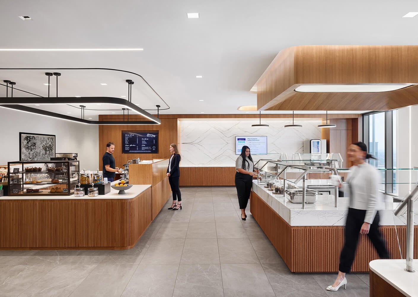 Servery interior with wooden elements and large windows. Staff serve customers at the counter, showcasing beverages and pastries.