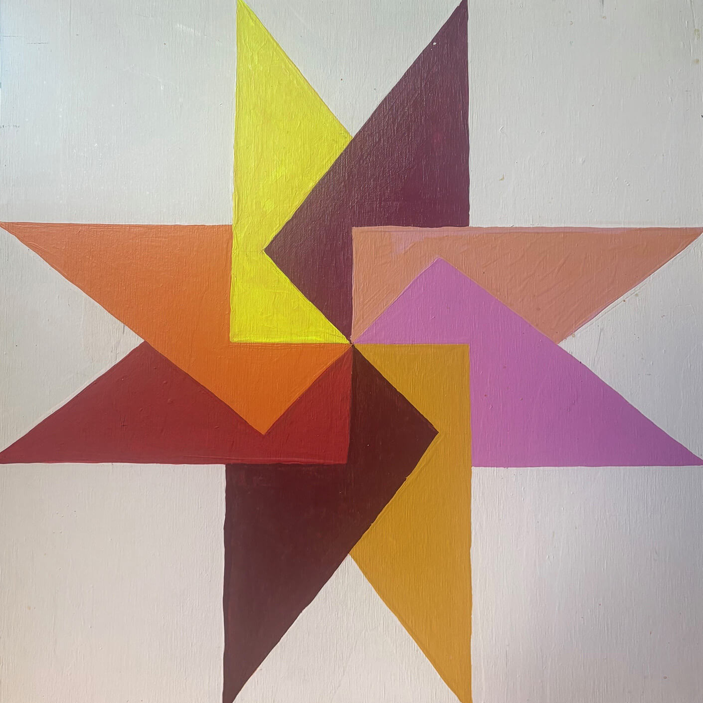 Colorful geometric star shape composed of various triangles in shades of yellow, orange, pink, and brown against a light background.