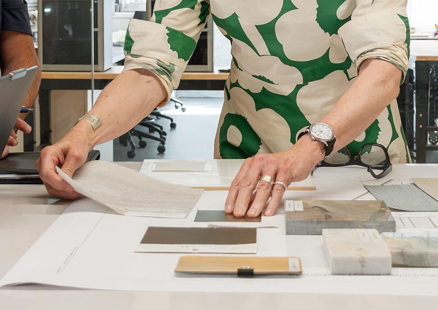 A person examines various materials and textures at a workspace, showcasing design options with color swatches and samples.