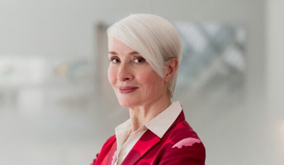 Headshot of Robin Osler with short white hair, wearing a red blazer, posing against a neutral background, showcasing a professional demeanor.