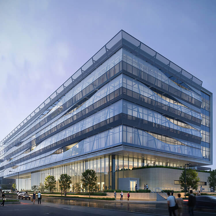 Contemporary glass and steel building with multiple levels, showcasing a sleek design and urban landscaping, busy with pedestrians and vehicles.