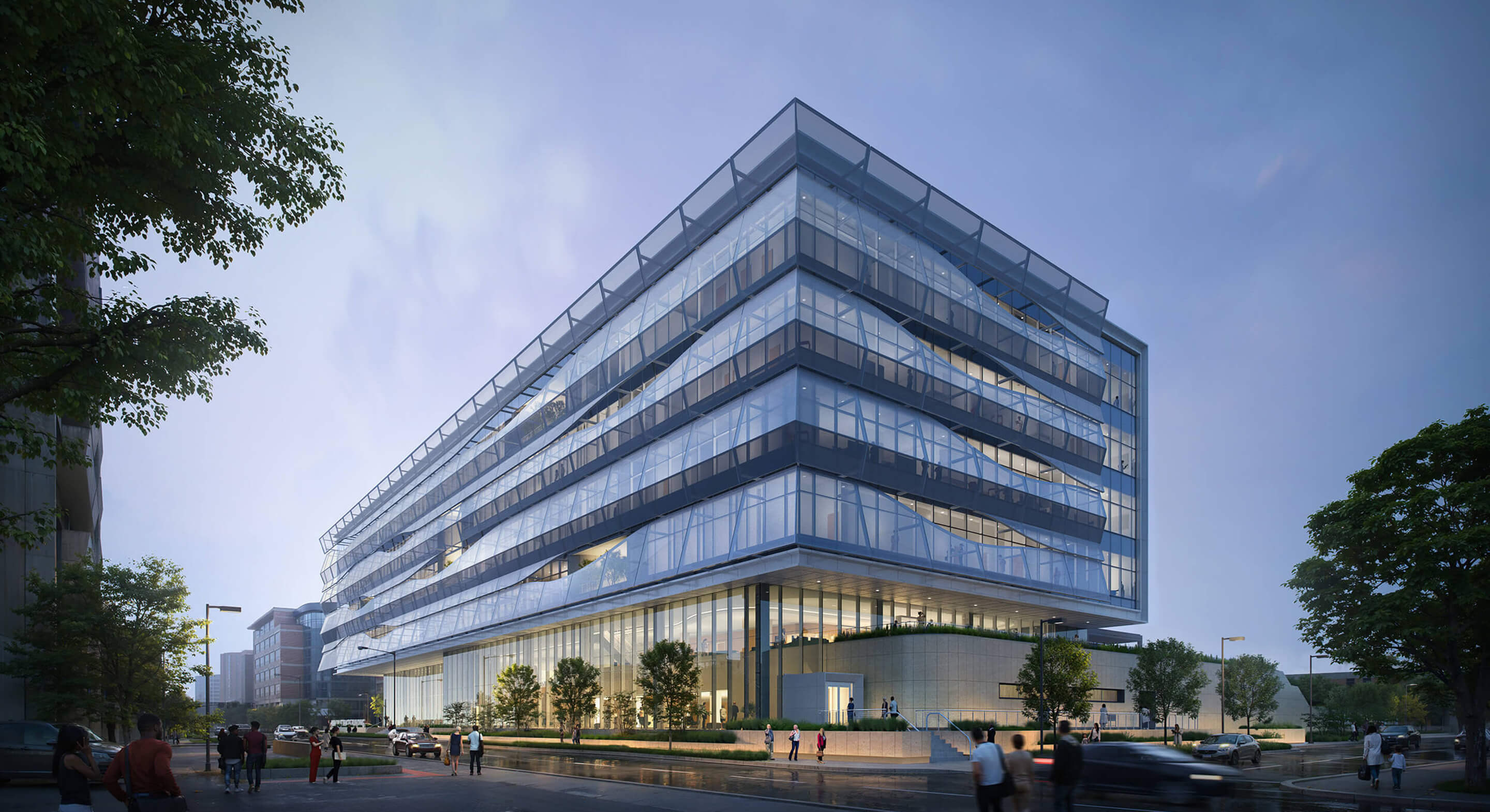 Architectural view of a glass office building with landscaped surroundings and pedestrians. Evening light highlights the structure's features.