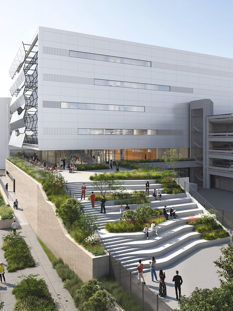 Exterior view of a large building featuring a landscaped area with stepped seating, greenery, and people engaging in various activities.
