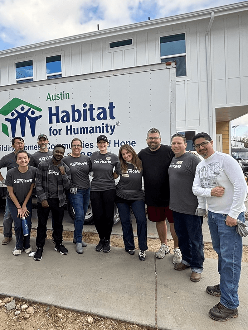 Group of volunteers posing at a Habitat for Humanity site in Austin, showing dedication to community service and teamwork.